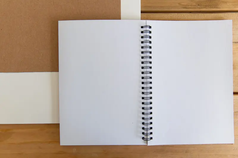 Cuaderno con espiral negro abierto sobre una mesa de madera