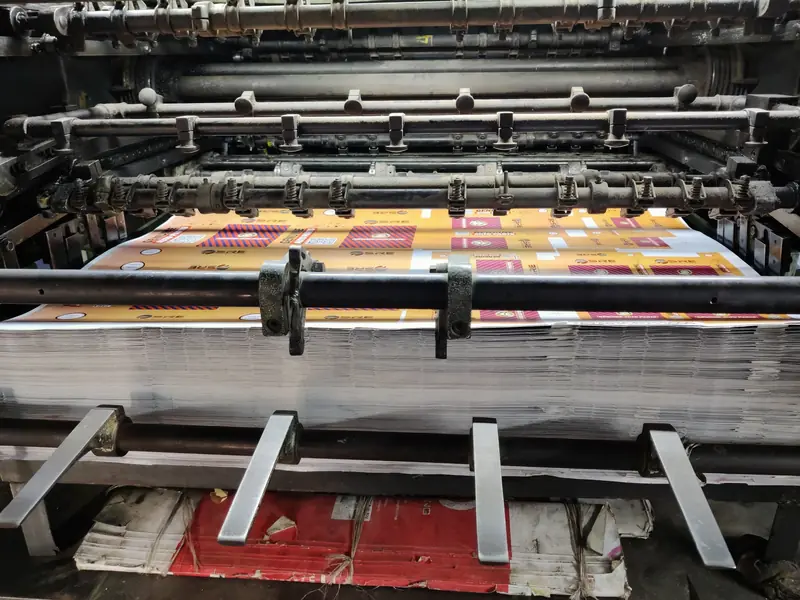 Prensa offset con una pila de pliegos impresos a todo color